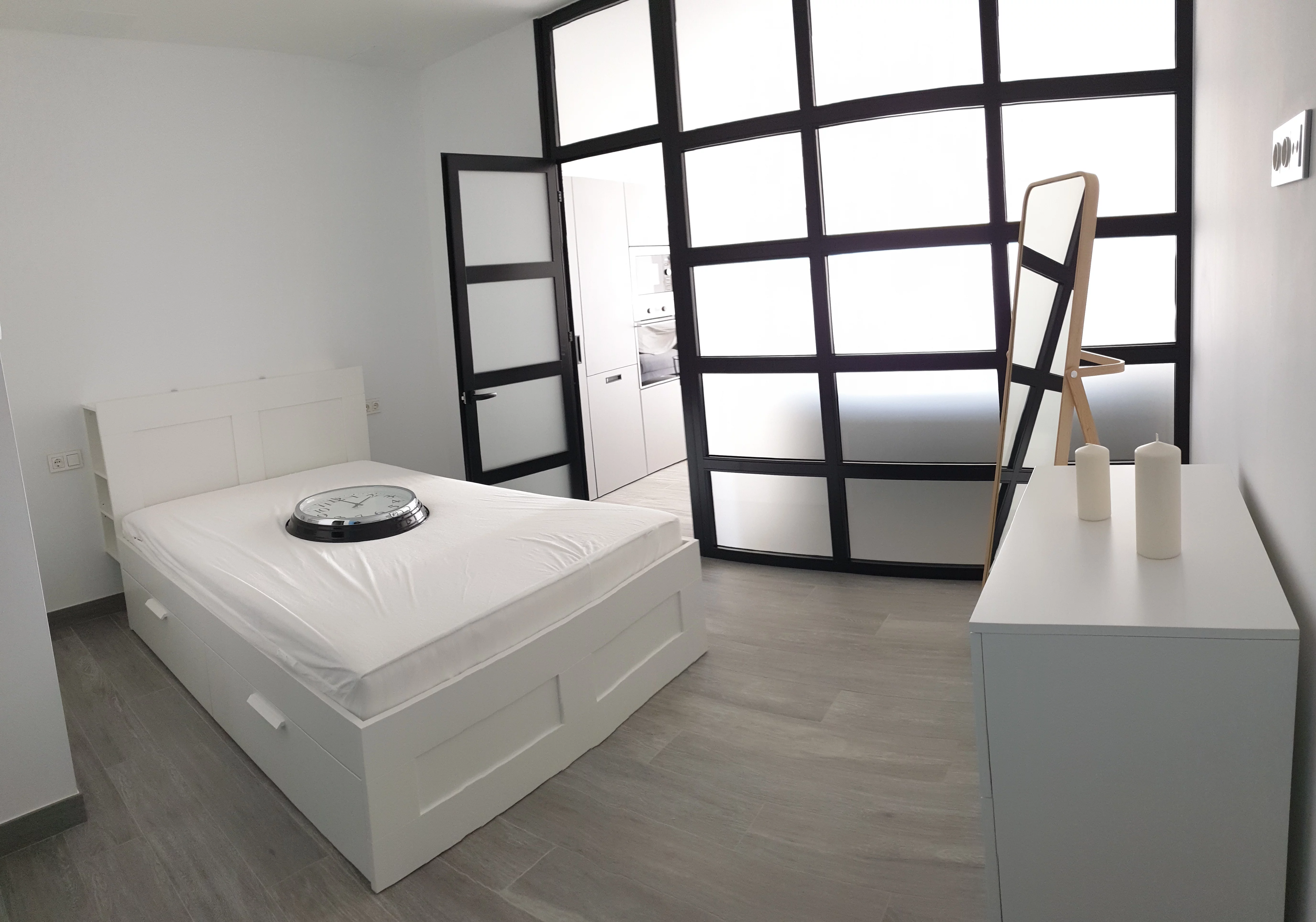 Dormitorio suite con cerramiento acristalado de perfilería negra en vivienda de Lepe