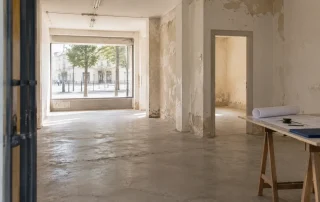 Visualización conceptual de un local vacío con luz desde la fachada y mesa de medición.