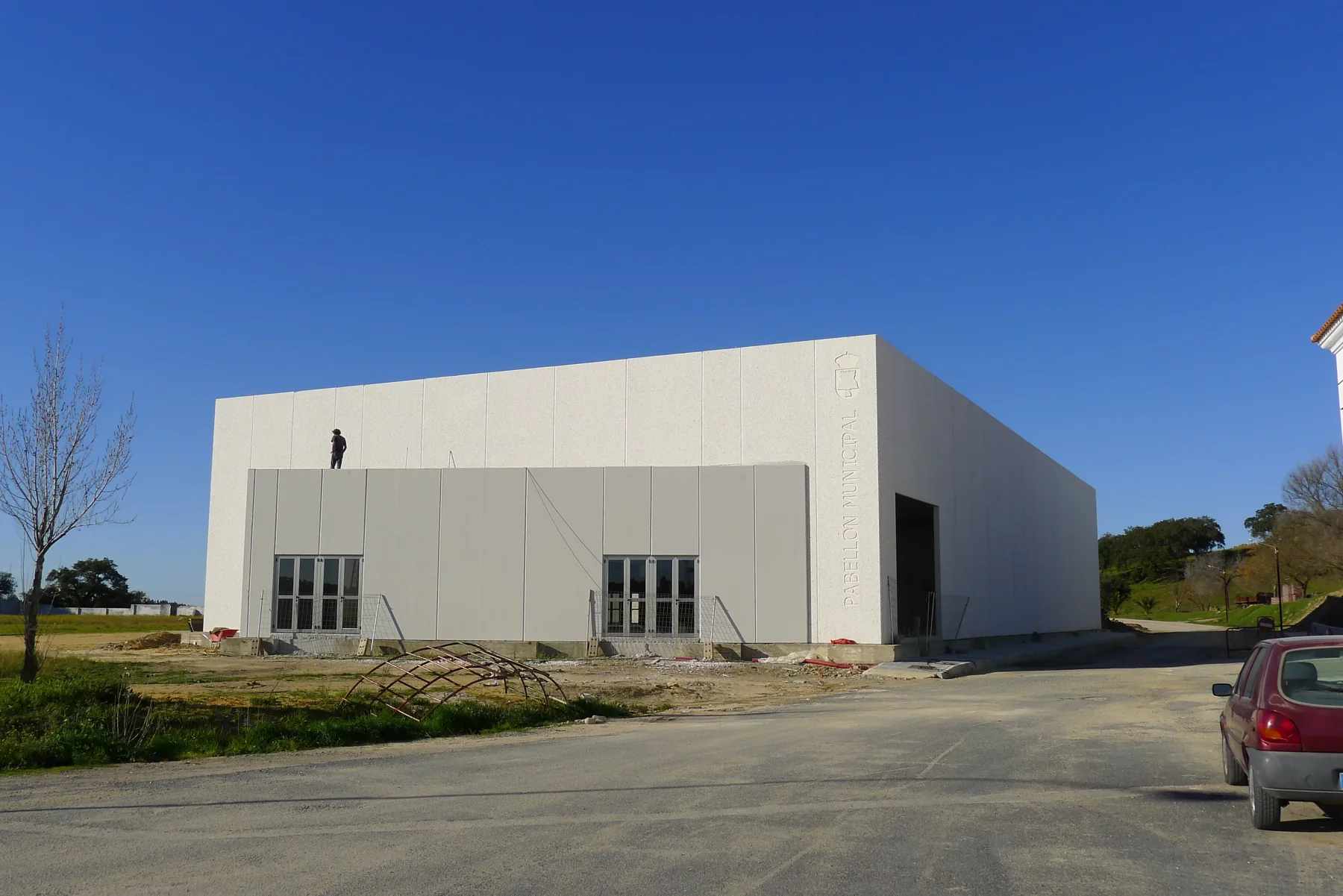 Fachada de paneles prefabricados de hormigón blanco del pabellón municipal de Santa Bárbara de Casa
